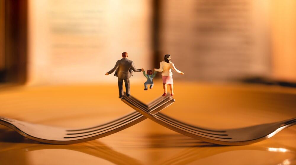 A cartoon graphic of two parents holding the hands of their child on two interlocked forks.